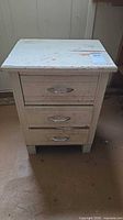 Front view showing three drawers, pulls, distressed finish