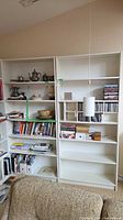 Both white bookcases side by side filled with books and decor
