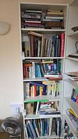 Full view of tall white laminate bookcase filled with books
