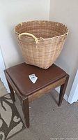 Wicker basket resting atop wood storage bench with vinyl seat