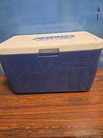 Front view of cooler showing blue body, Coleman logo, front latch