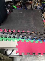 Stack of interlocking foam mats showing black surface and coloured edges