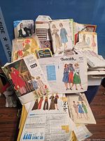 Group of assorted vintage women’s sewing patterns spread over bin