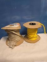 White nylon cord and yellow rope on spools side by side