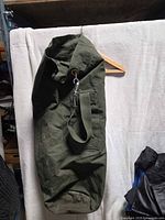 Full view of olive drab canvas duffle bag hanging to show overall shape and size