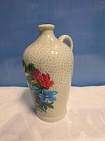 Side view of textured ceramic decanter with painted flowers