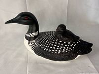 Side view of loon figurine showing adult with chick on back
