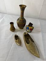 Group view of two brass vases, enamel bell, two brass shoe ashtrays