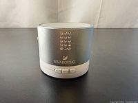 Front view of silver Swarovski speaker showing crystal accents and logo