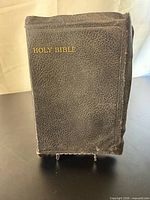 Front cover of black leather-bound Holy Bible on stand