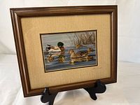 Full view of framed, matted print on stand