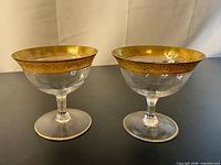 Two Tiffin-Franciscan Minton gold band sherbet glasses side by side