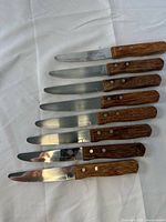 Eight of the ten identical Vollrath steak knives laid flat showing full view