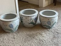 Front view of three porcelain planters showing floral painting