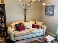 Full view of cream fabric sofa against wall with pillows