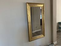 Full view of rectangular gold framed mirror mounted on wall