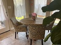 Round pedestal table with four patterned chairs in dining area