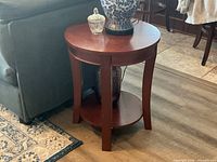 Round side table next to sofa showing top, legs and lower shelf