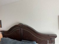Carved dark wood headboard of California king bed frame