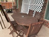 Full view of wood patio table with six folding chairs