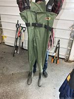 Front view of green chest waders held up, showing full length and suspenders