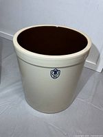 Front view of off-white stoneware crock with blue BB USA shield logo