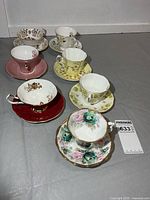 Seven teacup and saucer sets arranged in a line