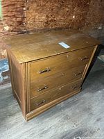Front view of wooden dresser showing three drawers with metal pulls