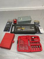 All items laid out: grey drill box, black socket set, red drill/driver set, Mastercraft hex keys, red vise