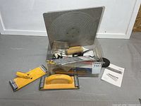 Group of drywall tools in bin with mud hawk, trowels, sanders, accessories