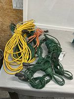 Assorted yellow, orange and green extension cords coiled on table