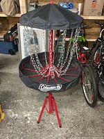 Full view of Coleman disc golf basket showing red metal frame, chains, black fabric top and basket