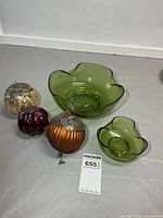 Lot overview showing both green glass bowls and three decorative spheres