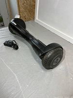 Side view of black GoTrax hoverboard with charger on table