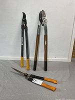 Three garden cutting tools standing on backdrop