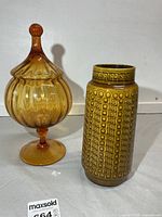Front view of amber glass candy dish with lid and pottery vase