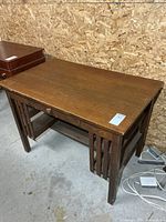 Angled front view of oak mission desk showing drawer, slatted sides, lower shelf
