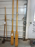 Pair of wooden oars standing vertically with rake for scale