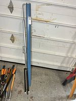 Full view of folded projector screen in blue case with support rod and folding legs