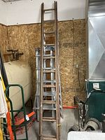 Full view of folded wooden extension ladder leaned against wall