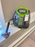 Front view of Bissell Little Green ProHeat spot cleaner with hose and tool attached