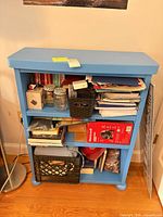 Front view of blue Ikea bookcase showing three shelves and rounded feet