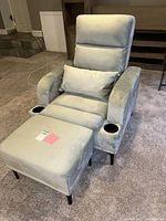 Front view of recliner fully reclined with ottoman, showing upholstery, cup holders, legs, pillow