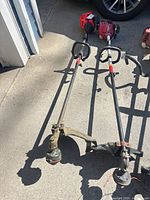 Both string trimmers full view with shafts, heads and guards visible