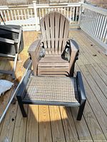 Brown plastic Adirondack chair with matching resin wicker ottoman on deck