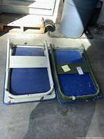 Two folded Olympia platform trucks side by side showing blue decks and differing frame colors