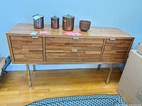 Front view of walnut veneer credenza on stainless legs