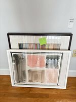 Both framed artworks front view leaning against wall