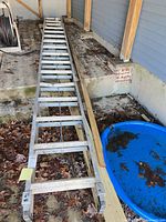 Full view of Werner aluminum extension ladder lying collapsed showing overall length and two-section design