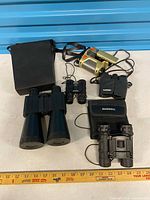 Group shot showing all binoculars, night scope, and cases